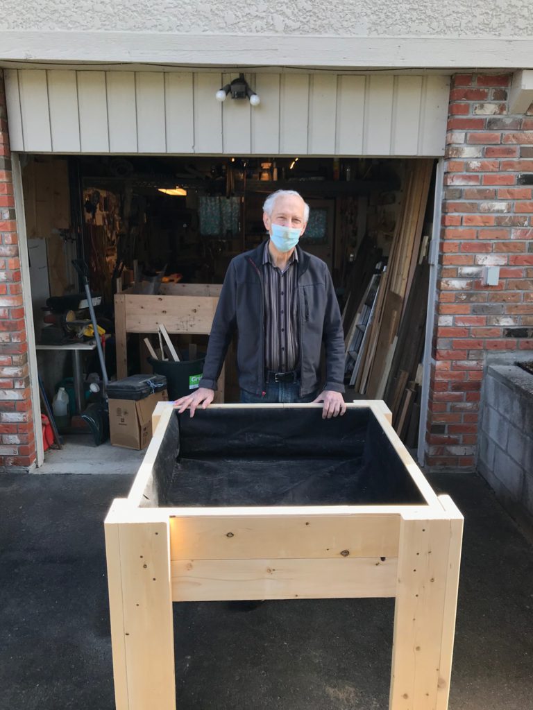 George posing with handmade raised garden bed designed for DIGA.