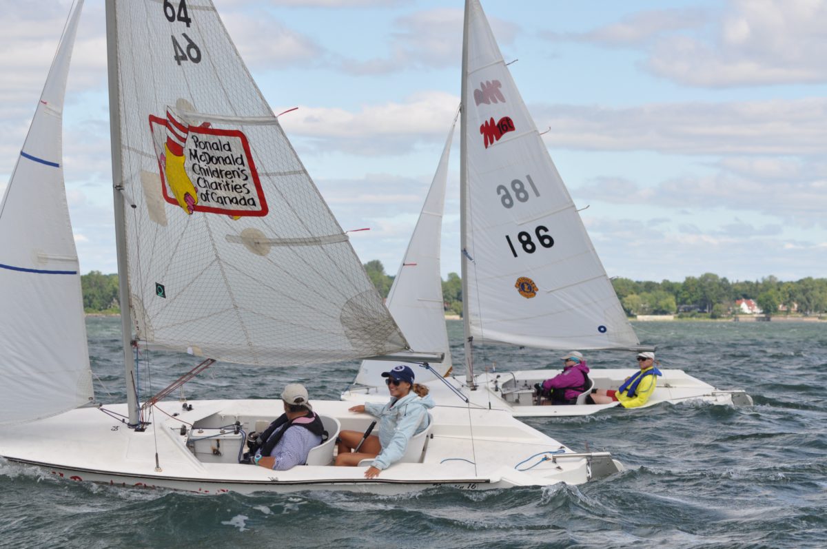 Two pairs of people are racing two Martin 16 sailboats